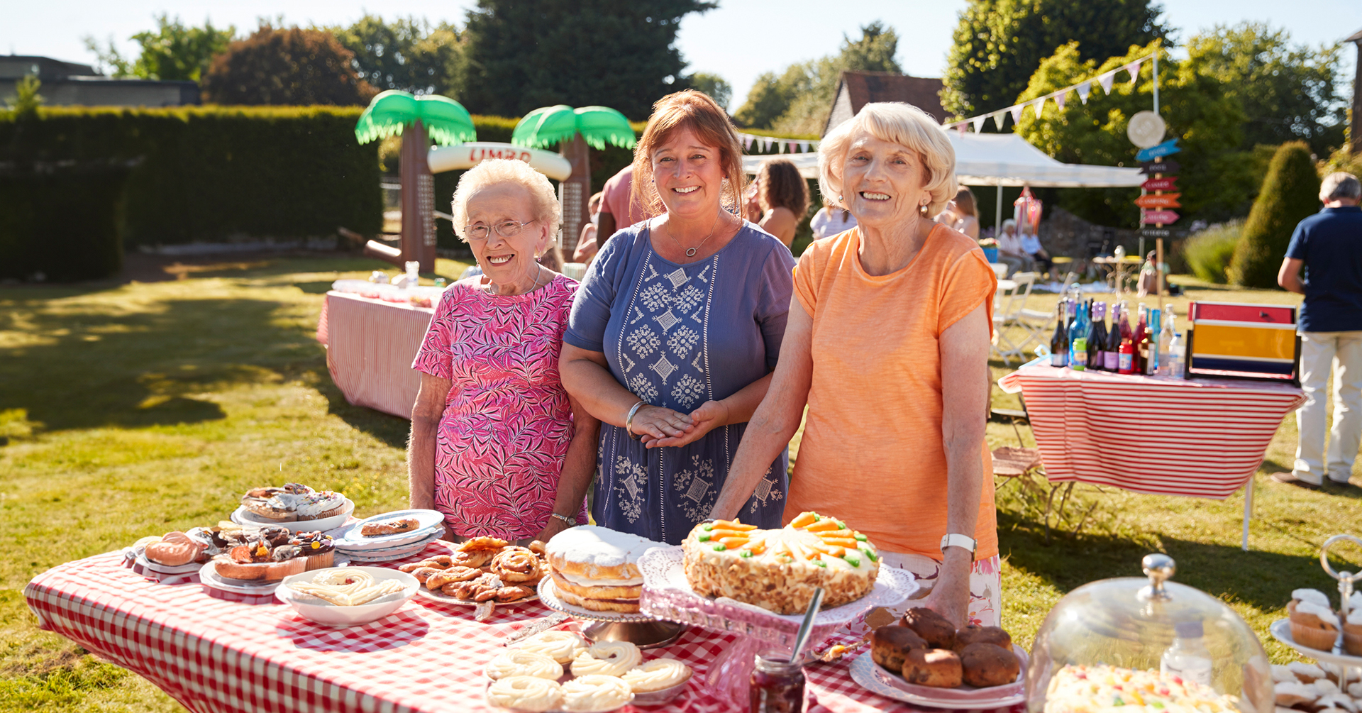 2 seniors with a mature adult at a summer outdoor celebration picnic