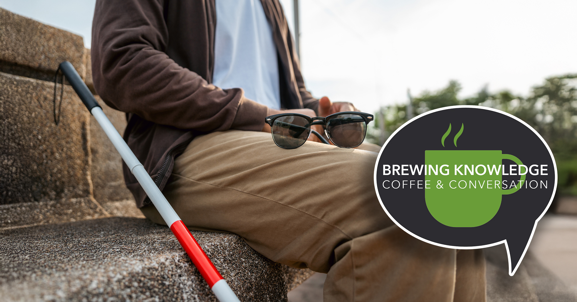 a vision-impaired older adult sitting on a bench with a cane next to him